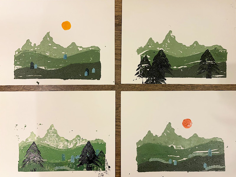 Four prints of a green mountain landscape with small houses and a sun or moon in the sky, each with slight variations in tree placement, color shades, and sky color.